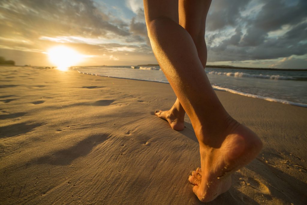 A person walking on the beach at sunset.